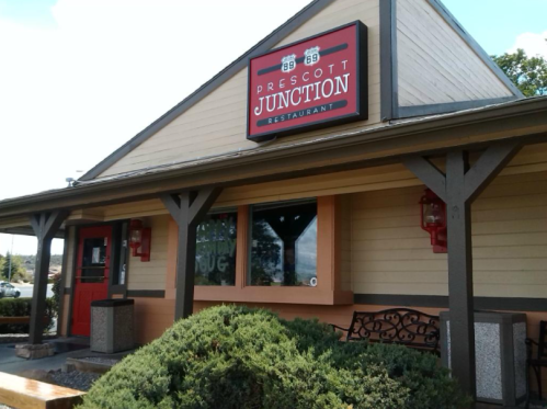 Exterior of Prescott Junction Restaurant featuring a sign, wooden beams, and a landscaped entrance.