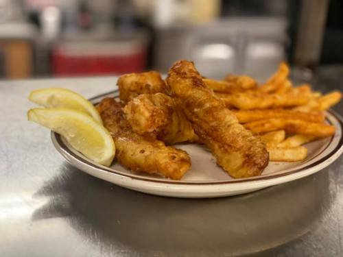 A plate of golden fried fish sticks and crispy French fries, garnished with lemon wedges.