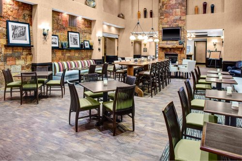 A spacious dining area with wooden tables, chairs, and a stone wall, featuring cozy seating and decorative lighting.