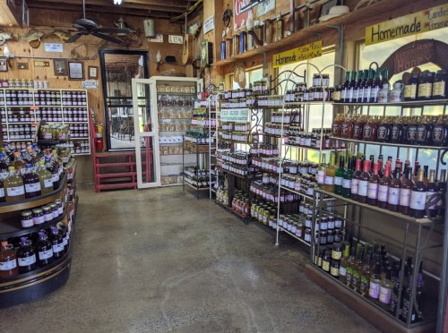 A cozy shop interior filled with shelves of homemade jams, sauces, and various bottled products.