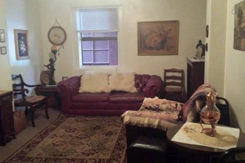Cozy living room with a red leather sofa, decorative pillows, a rug, and various artwork on the walls.