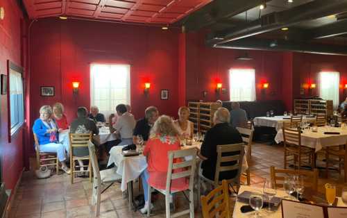 A cozy restaurant interior with red walls, tables set for dining, and patrons enjoying their meals.