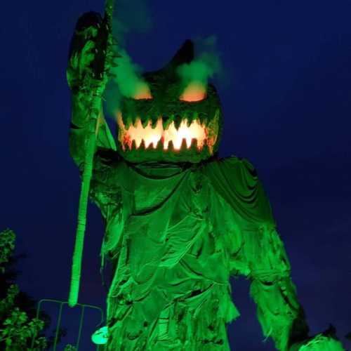 A large, eerie figure with glowing eyes and smoke, standing in a dark setting, holding a staff.