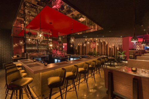 Stylish bar interior with modern seating, dim lighting, and a vibrant red ceiling, creating a cozy atmosphere.