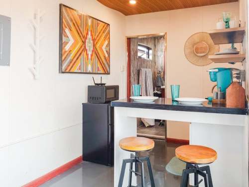 Cozy kitchen with a black countertop, two stools, and colorful decor, leading to a bathroom area.