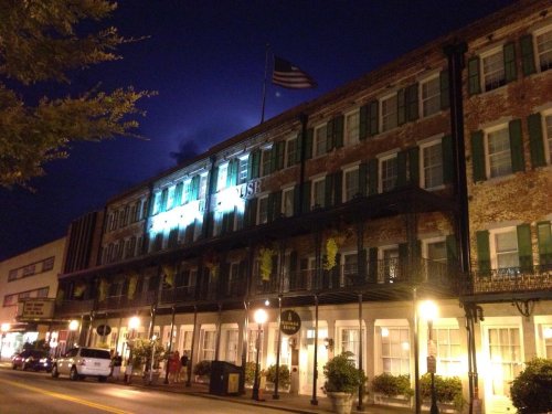 Historic building at night with American flag, green shutters, and street lamps illuminating the scene.