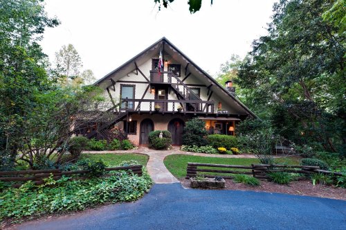 A charming, multi-level house surrounded by lush greenery and a winding path leading to the entrance.