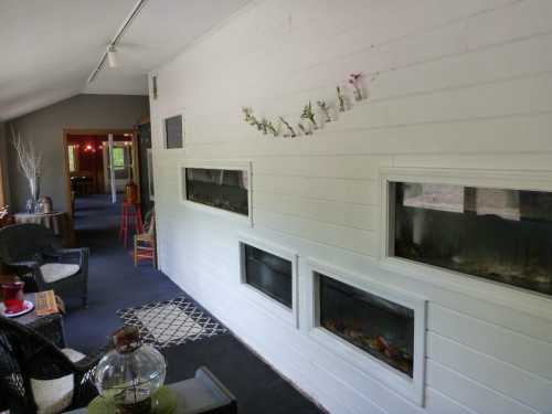 A cozy interior with white walls, three built-in fireplaces, and a seating area featuring black chairs and a decorative table.