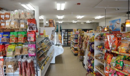 A well-stocked convenience store aisle with snacks, candies, and packaged goods on display.
