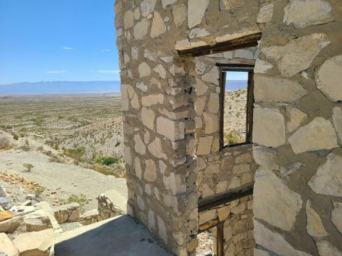 A view from a stone building overlooking a vast desert landscape under a clear blue sky.