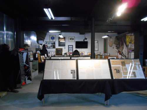 A museum exhibit featuring framed documents and artwork, with dark walls and various displays in the background.