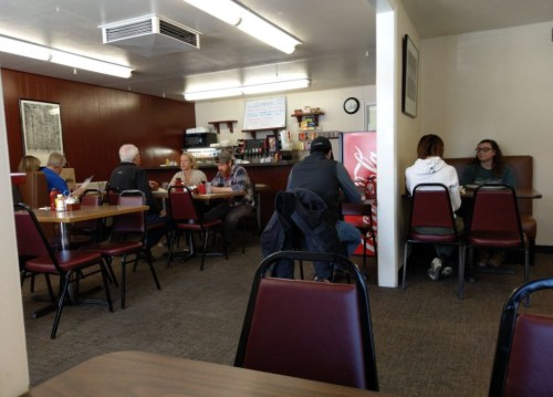 A cozy diner interior with patrons seated at tables, enjoying meals and conversations in a casual atmosphere.