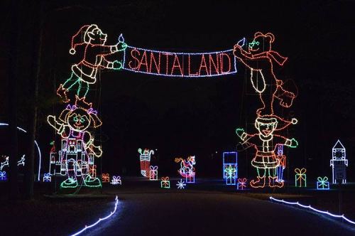 Colorful holiday lights create an archway reading "Santaland," featuring festive characters and decorations.