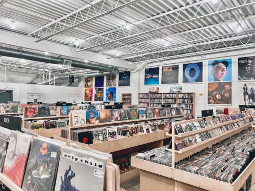 A spacious record store with rows of vinyl albums and colorful posters on the walls.