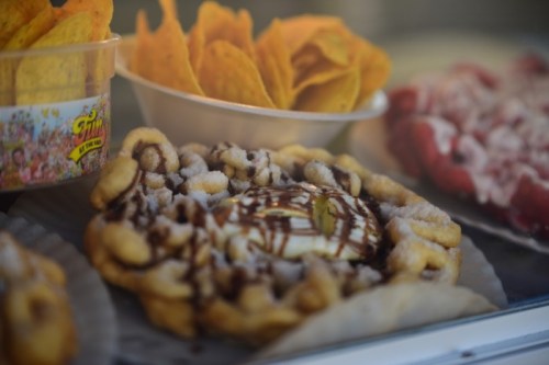 A close-up of a dessert featuring a circular pastry drizzled with chocolate and surrounded by crispy snacks.