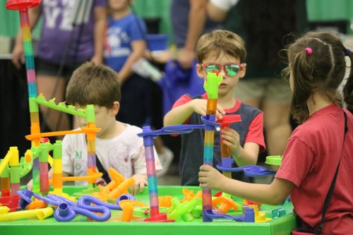 Children playing with colorful building toys at a table, focused on constructing various structures.