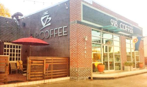 Exterior of 918 Coffee shop featuring a patio with an umbrella and large glass windows.