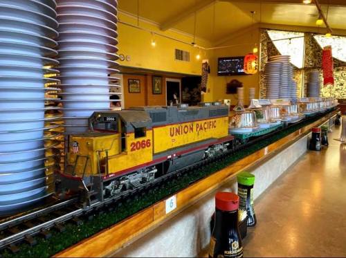 A model train labeled "Union Pacific" runs along a restaurant counter, surrounded by decorative elements and condiments.