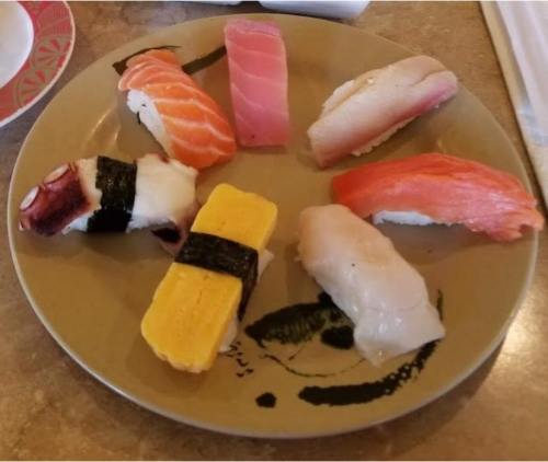 A plate of assorted sushi, featuring various types of fish and a slice of tamago, arranged neatly.