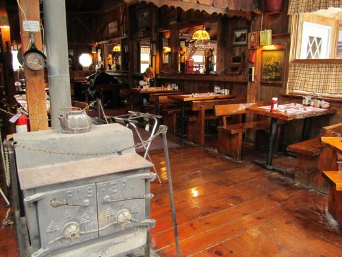 Cozy rustic restaurant interior with wooden tables, a vintage stove, and warm lighting.