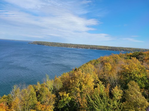A scenic view of a lake surrounded by colorful autumn foliage under a clear blue sky.