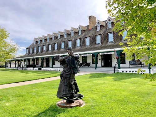 A historic building with a grassy lawn and a bronze statue of a couple dancing in the foreground.