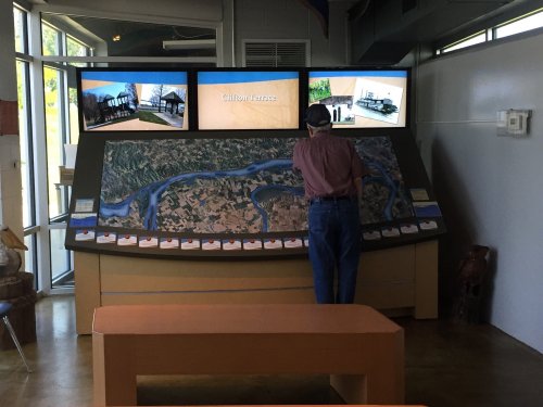 A person examines a large map display with screens showing images and information about a location.