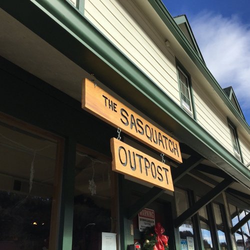 Sign for "The Sasquatch Outpost" on a building with a green exterior and wooden accents.