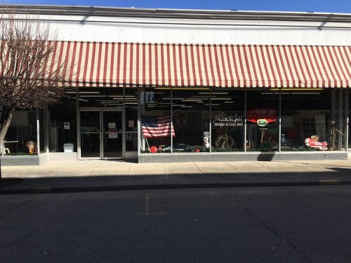 A storefront with large windows, striped awning, and various signs, including an American flag and colorful displays.