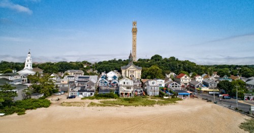 view of a sandy beach, shops and restaurants along commercial street and the pilgrim monument in Provincetown massachusetts