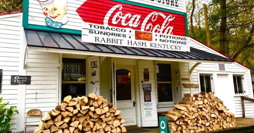 A quaint store in Rabbit Hash, Kentucky, featuring a Coca-Cola sign and stacked firewood outside the entrance.