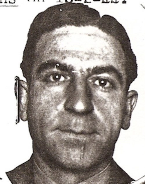 Black and white portrait of a man with short hair, wearing a collared shirt, looking directly at the camera.