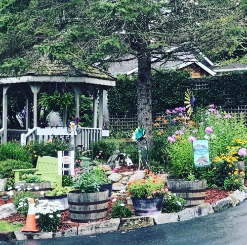 A charming garden with colorful flowers, a gazebo, and decorative elements, surrounded by greenery and a peaceful atmosphere.