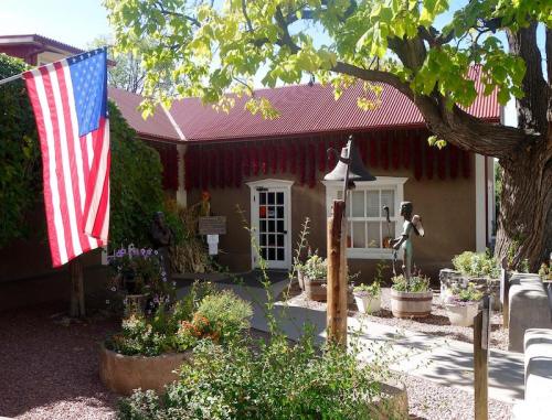 A quaint building with a red roof, surrounded by greenery and flowers, featuring an American flag in the foreground.