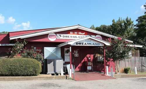 Exterior of Dreamland BBQ restaurant, featuring a red building with signage and a welcoming entrance.