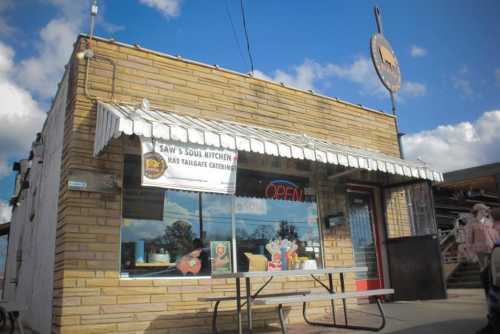 A brick building with an awning, featuring a sign that says "Saw's Soul Kitchen" and an open sign in the window.