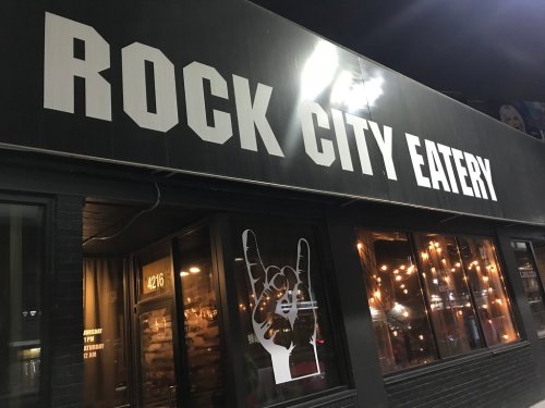 Sign for "Rock City Eatery" with a hand gesture and illuminated windows at night.