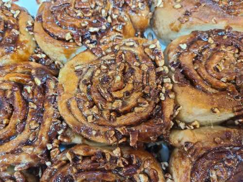Close-up of freshly baked cinnamon rolls topped with caramel and chopped nuts.