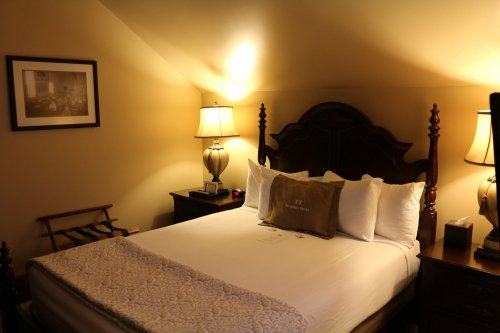 Cozy bedroom with a large bed, decorative pillows, bedside tables, and warm lighting.