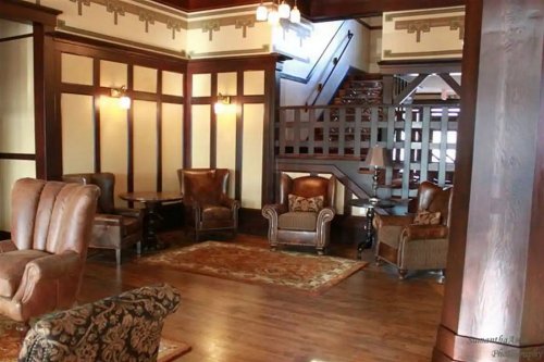 Cozy interior of a room with leather armchairs, a rug, and a staircase in a warm, inviting setting.