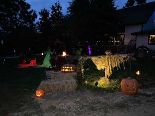 A spooky Halloween scene with ghost decorations, pumpkins, and eerie lighting in a dark yard.