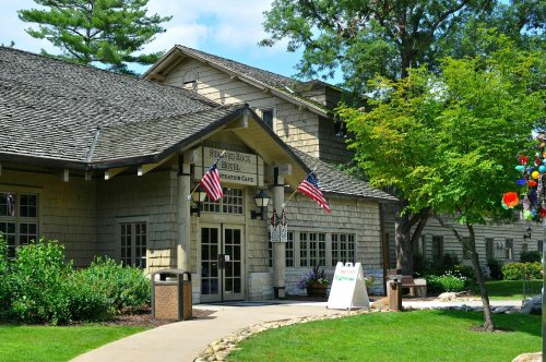 A charming building with a stone facade, surrounded by greenery and flags, featuring a welcoming entrance and pathway.