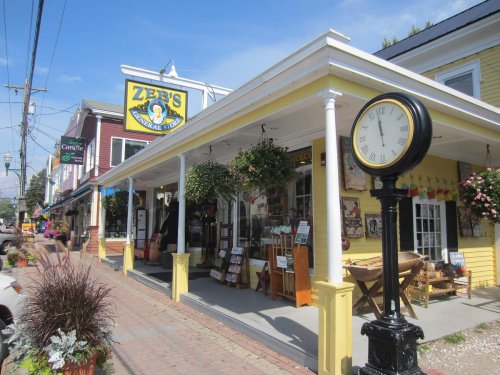 A charming storefront with a yellow sign reading "Zeb's General Store," featuring hanging plants and a vintage clock.