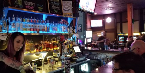 A lively bar scene with a bartender serving drinks, colorful bottles on shelves, and patrons enjoying the atmosphere.
