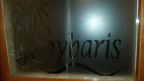 Frosted glass door with the word "Sybaris" and a palm tree design.