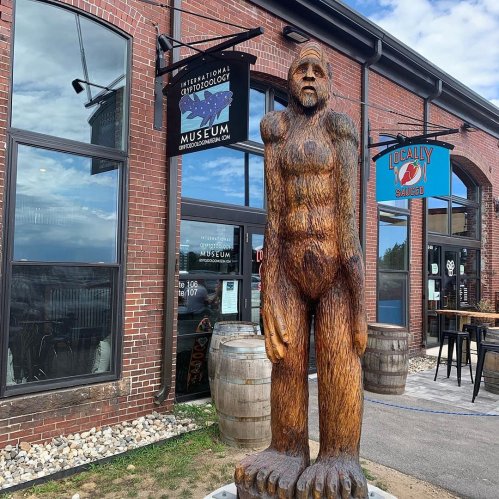 A tall wooden statue of a Bigfoot-like figure stands outside the International Cryptozoology Museum.