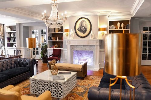 A cozy living room with a chandelier, fireplace, and elegant furniture, featuring a mix of modern and classic decor.