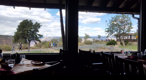 View from a restaurant window showing a scenic landscape with trees and people walking outside.