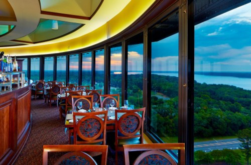 Elegant restaurant interior with panoramic windows showcasing a scenic view of the landscape and sunset.