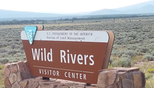 Sign for Wild Rivers Visitor Center, U.S. Department of the Interior, surrounded by a vast landscape of sagebrush.